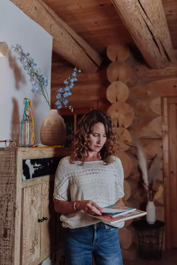 Claudia Burger steht mit Zeitschriften im Zimmer und blättert diese durch